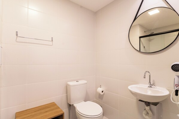 A bathroom with a toilet, sink, mirror, and towel rack.