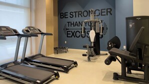 A gym with treadmills, a weight machine, and a motivational wall. - Raízes Tatuapé (São Paulo)