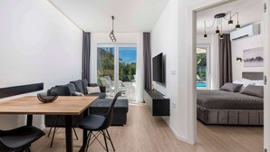 Ein modernes Wohnzimmer mit Essbereich, einer Couch, einem Fernseher und einem Bett.