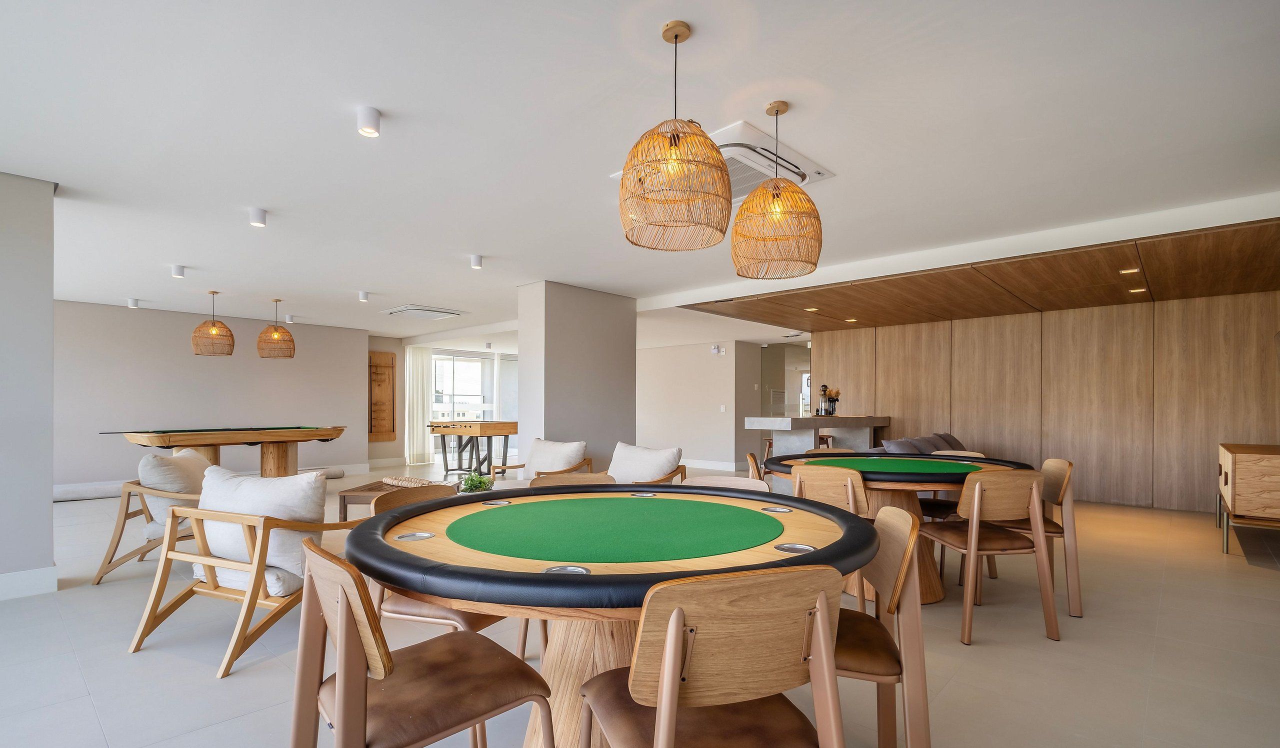 Un área recreativa moderna en interior con mesas de billar, asientos cómodos e iluminación elegante.