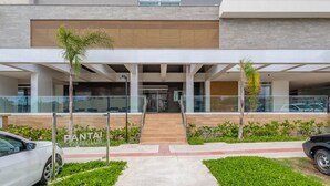 A modern building with a covered entrance, glass railings, and a sign for "FANTAI HOMECLUB". - Cond. c/ Academia a apenas 200 m da Praia de Piçarras - PTCs (Picarras)