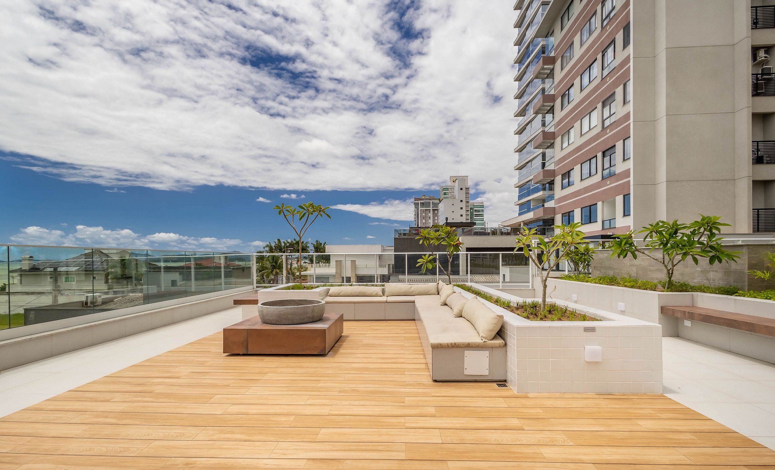 A rooftop terrace with a wooden floor, outdoor seating, and a view of the city skyline.