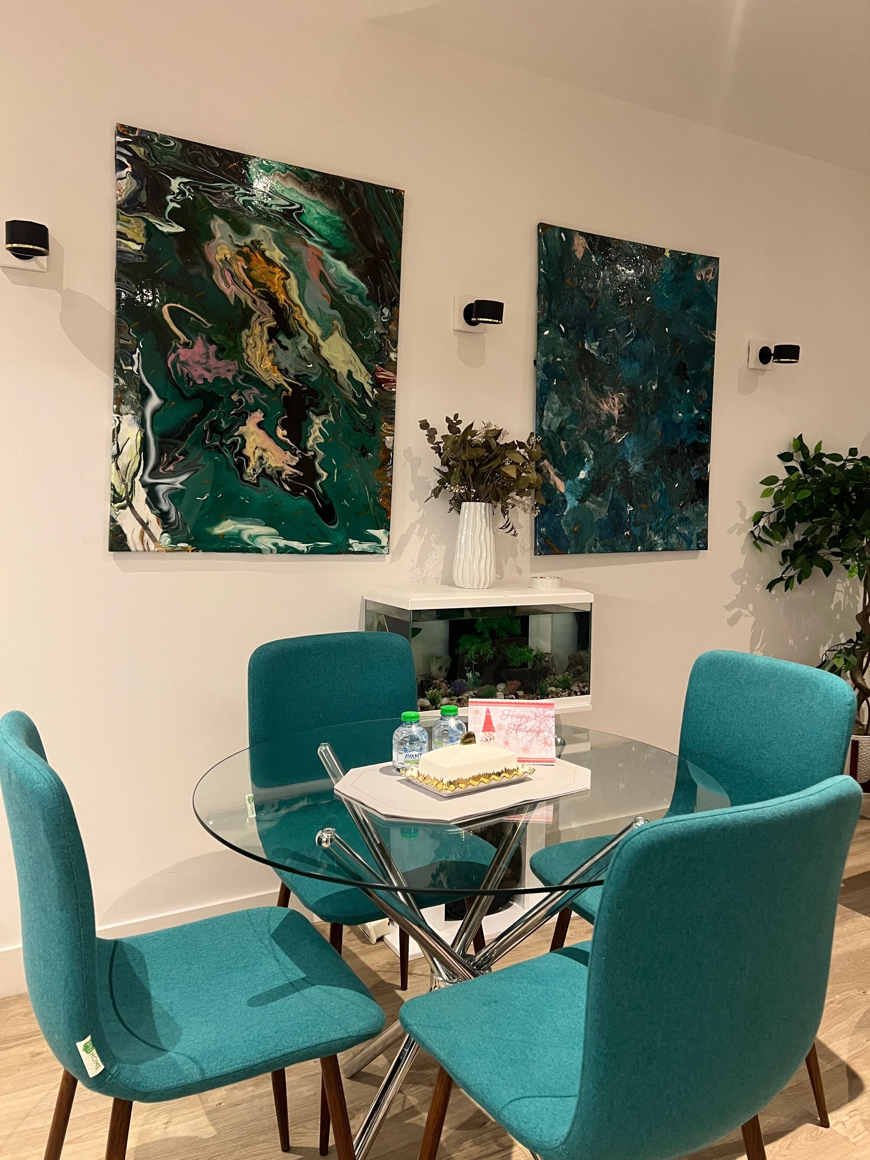 Una sala de reuniones moderna con sillas color turquesa, una mesa de vidrio y arte abstracto en las paredes.
