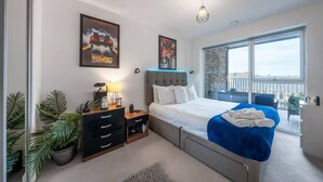 Une chambre à coucher moderne, avec un lit, une table de chevet, une commode et une grande fenêtre donnant sur un balcon.