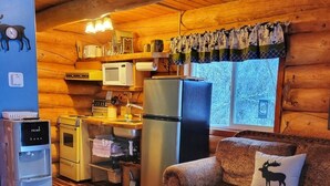 A cozy log cabin interior with a kitchen, a sofa with a moose pillow, and a patterned rug. - ^^LOG CABIN ON THE RIVER! Alaskan Aurora Adventure (Fairbanks)