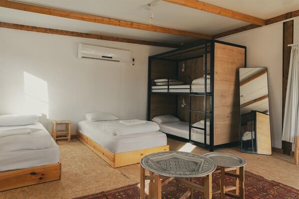 A room with two beds, a small table, and a mirror.