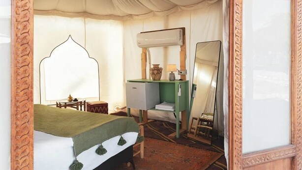 Ein Zimmer mit einem Bett, einem Schreibtisch, einem Stuhl, einem Spiegel und einer Klimaanlage.