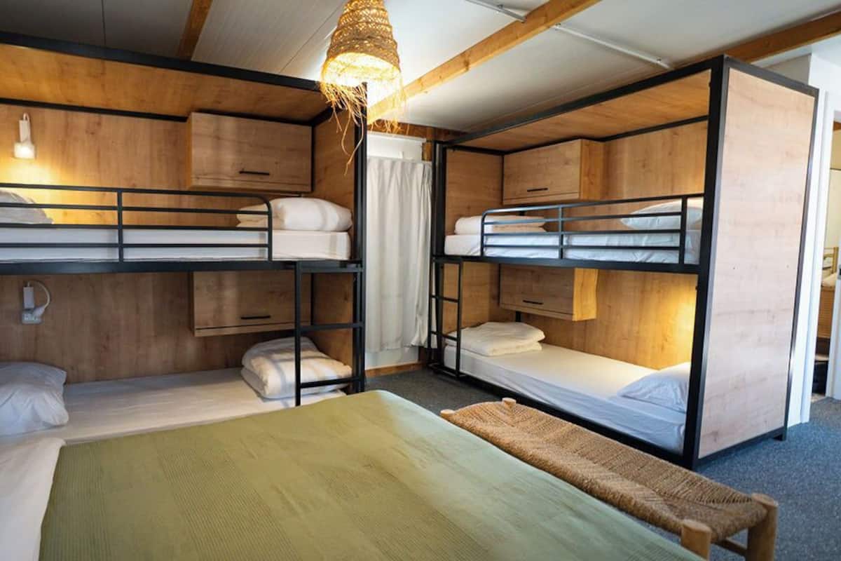 Une chambre avec des lits superposés, des murs en bois et un luminaire suspendu.
