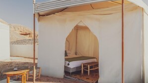 Ein Zeltraum mit einem Bett, einem kleinen Tisch und einem Stuhl.