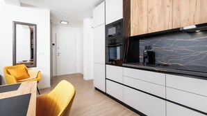 A modern kitchen with white cabinetry, a black countertop, and a wooden accent wall. - 1 bedroom apartment A4 in Villa Marealto with pool and garage (Ičići)