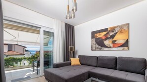 A modern living room with a grey sectional sofa, a glass coffee table, and a large abstract painting on the wall. - 1 bedroom apartment A4 in Villa Marealto with pool and garage (Ičići)