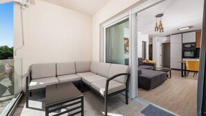 A modern living space with a sectional sofa, a small table, and a kitchen area visible through a glass door. - 1 bedroom apartment A4 in Villa Marealto with pool and garage (Ičići)