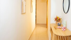 Un pasillo con suelo de madera, una mesa redonda con adornos y una lámpara colgante.