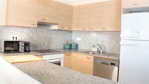 Una cocina moderna con encimeras de granito, electrodomésticos de acero inoxidable y armarios de madera clara.