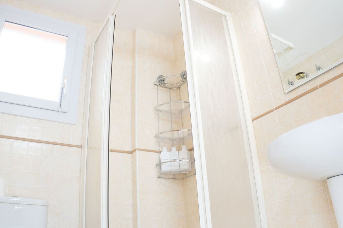 A bathroom with a shower, a toilet, and a window.