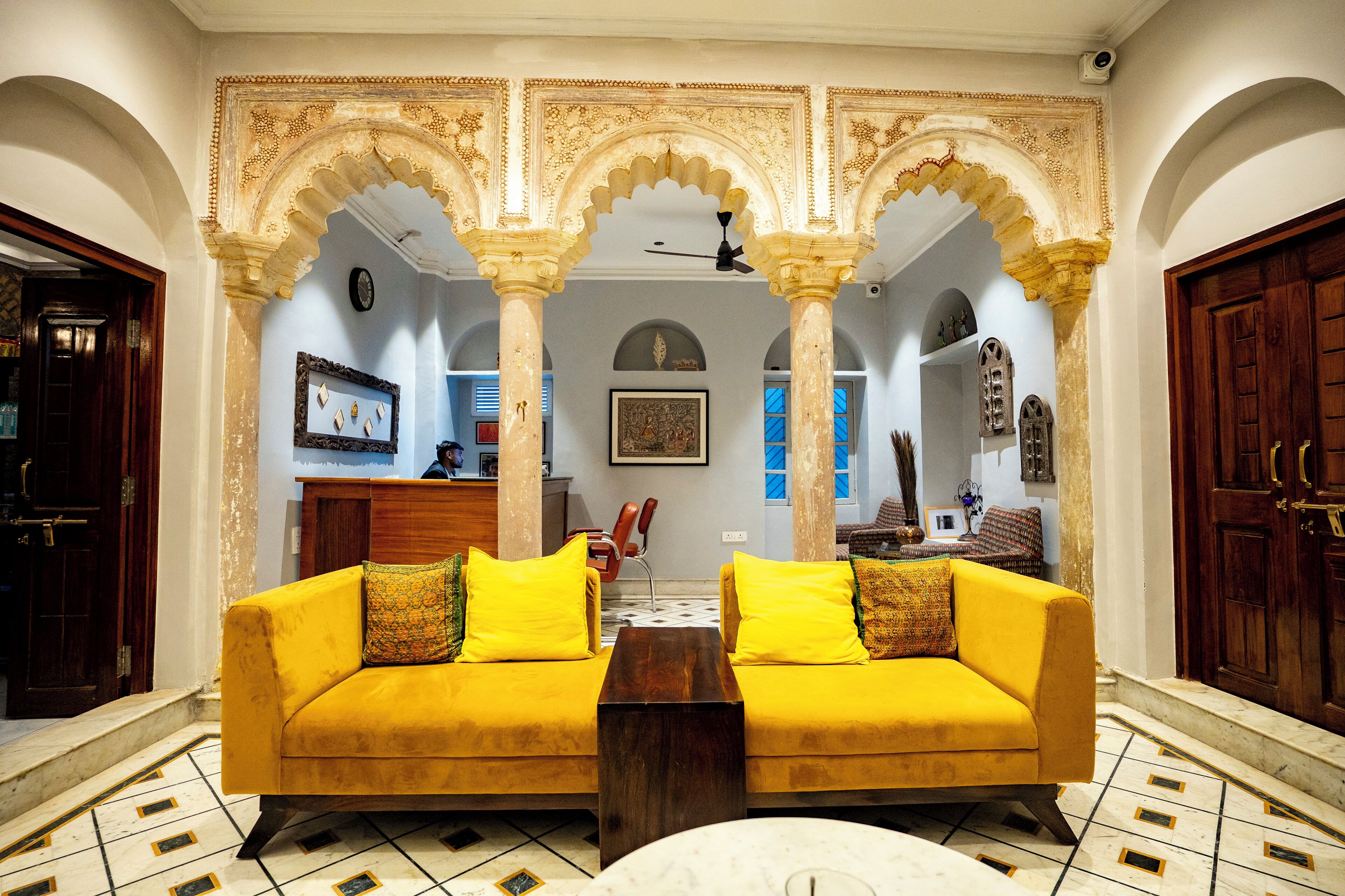 Una sala de estar con un sofá amarillo, una mesa de centro y un arco decorativo.