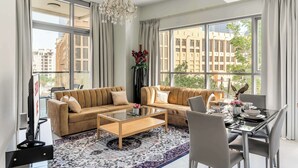 A modern living room with a sofa set, a coffee table, and a dining table with chairs. - StayShort - Downtown 2 Bed Unit with Burj Views that Sleeps 4 (Downtown)