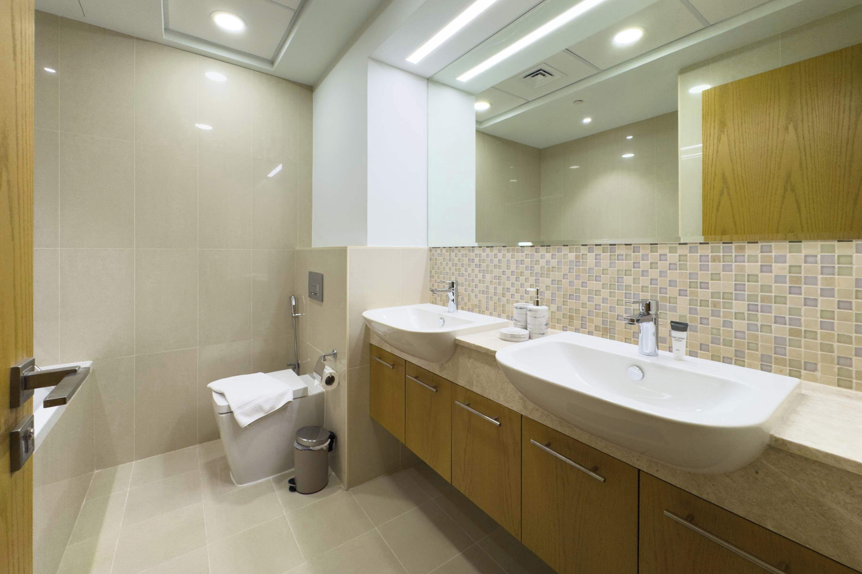 Une salle de bain moderne avec deux lavabos, des toilettes et une poubelle.