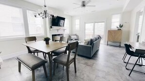 A spacious living area with a dining table, chairs, a sofa, and a ceiling fan. - Beach Block heart of Downtown Walk to Everything (Sea Isle City)