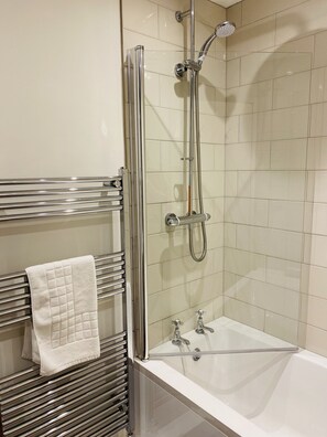 A modern bathroom with a glass-enclosed shower, a white bathtub, and a towel rack with a folded towel. - The Oaks Hotel (Alnwick)