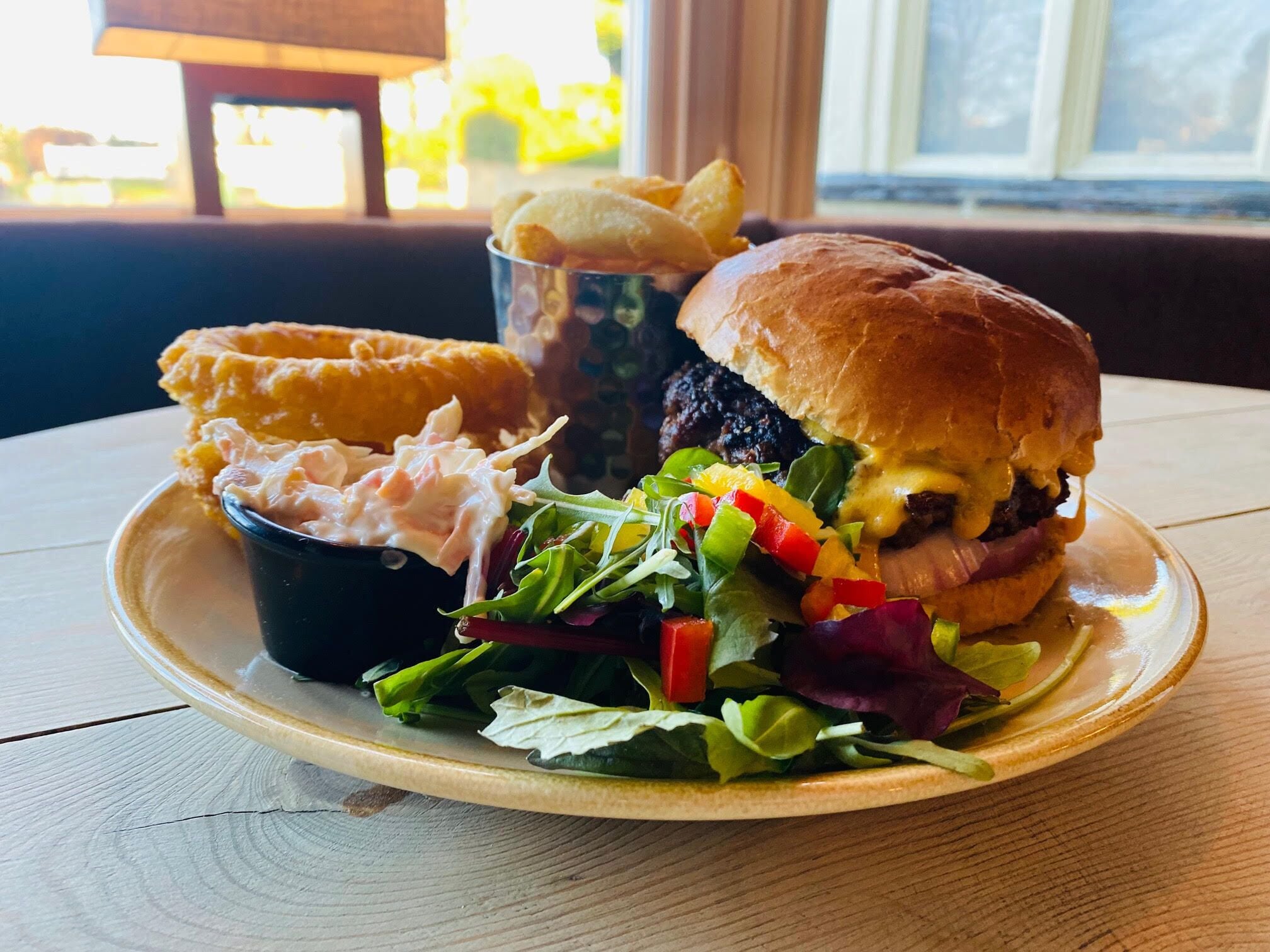 A plate with a burger, salad, and onion rings.