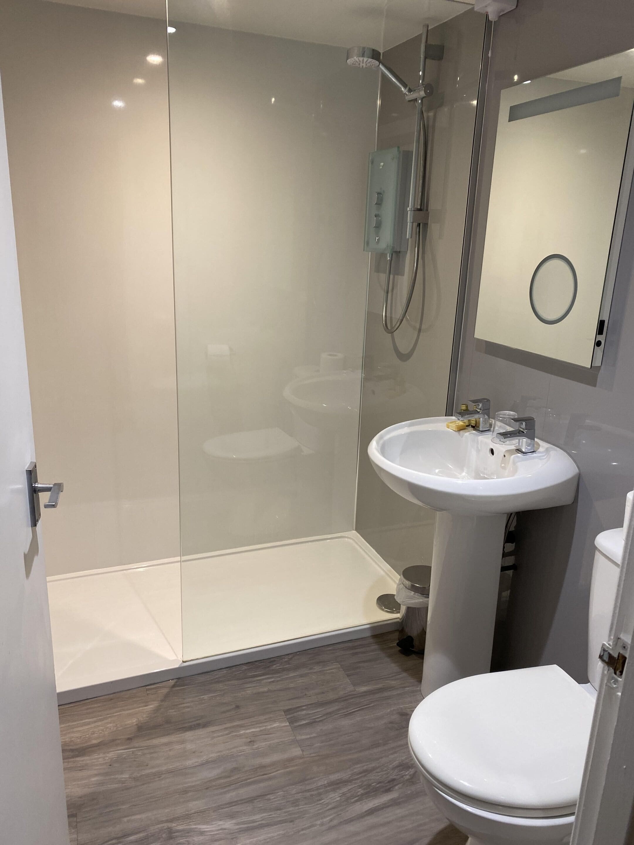 Une salle de bain moderne avec une douche à parois de verre, un lavabo blanc et des toilettes.