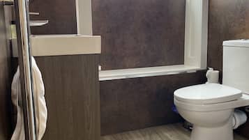 Un bagno moderno con un mobile bagno in legno, un water e una finestra che lascia entrare luce naturale.