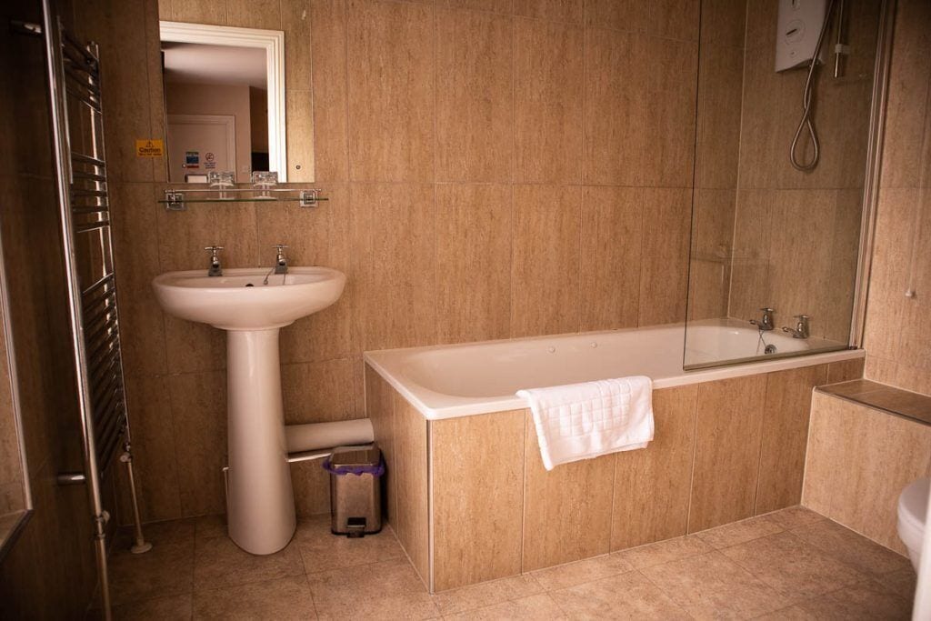 A bathroom with a pedestal sink, a bathtub, and a shower.