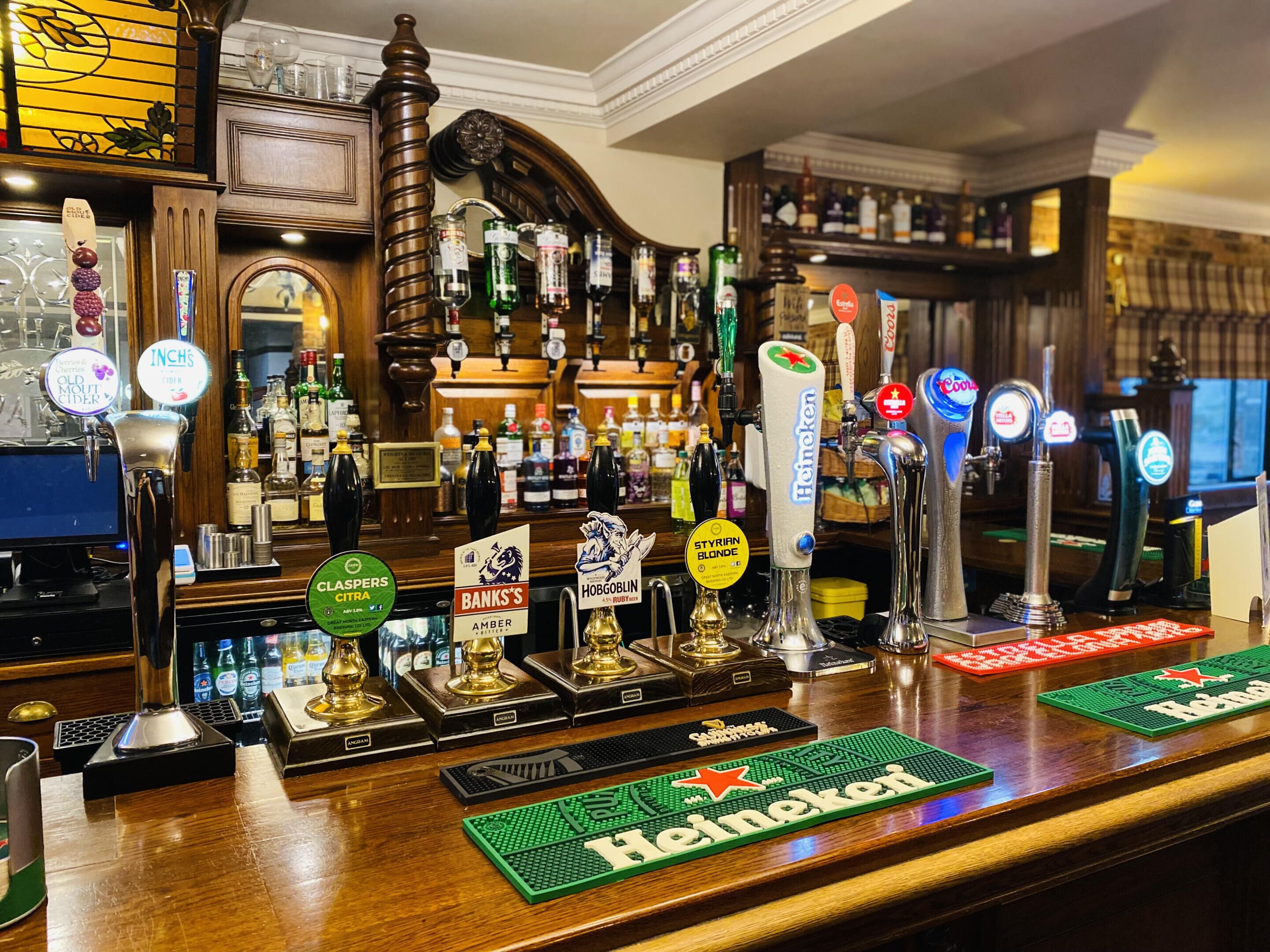 A bar with multiple beer taps, including brands like Heineken and Stella Artois, and a variety of liquor bottles in the background.