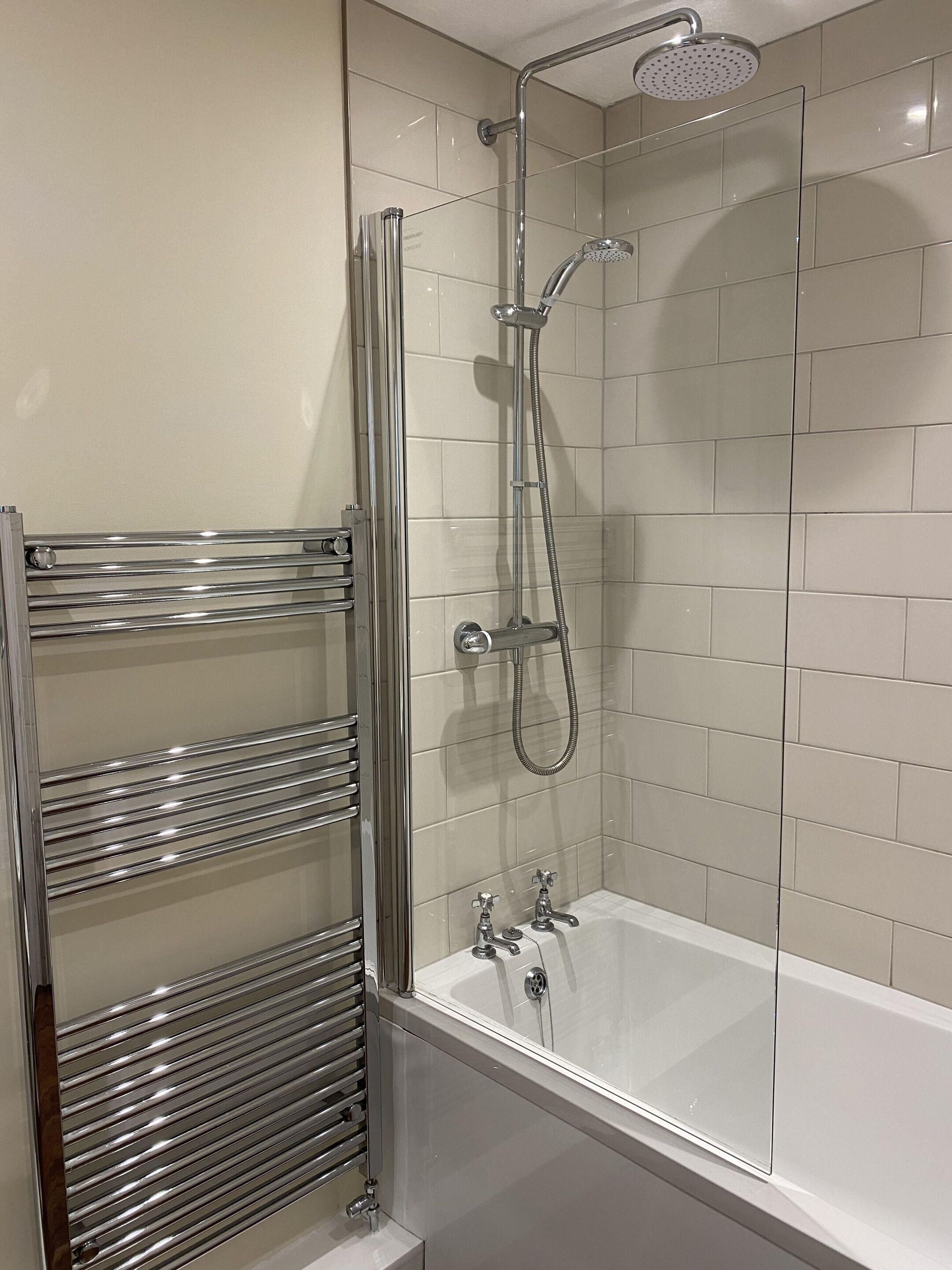 A modern bathroom with a glass-enclosed shower, a separate bathtub, and a chrome towel rack.