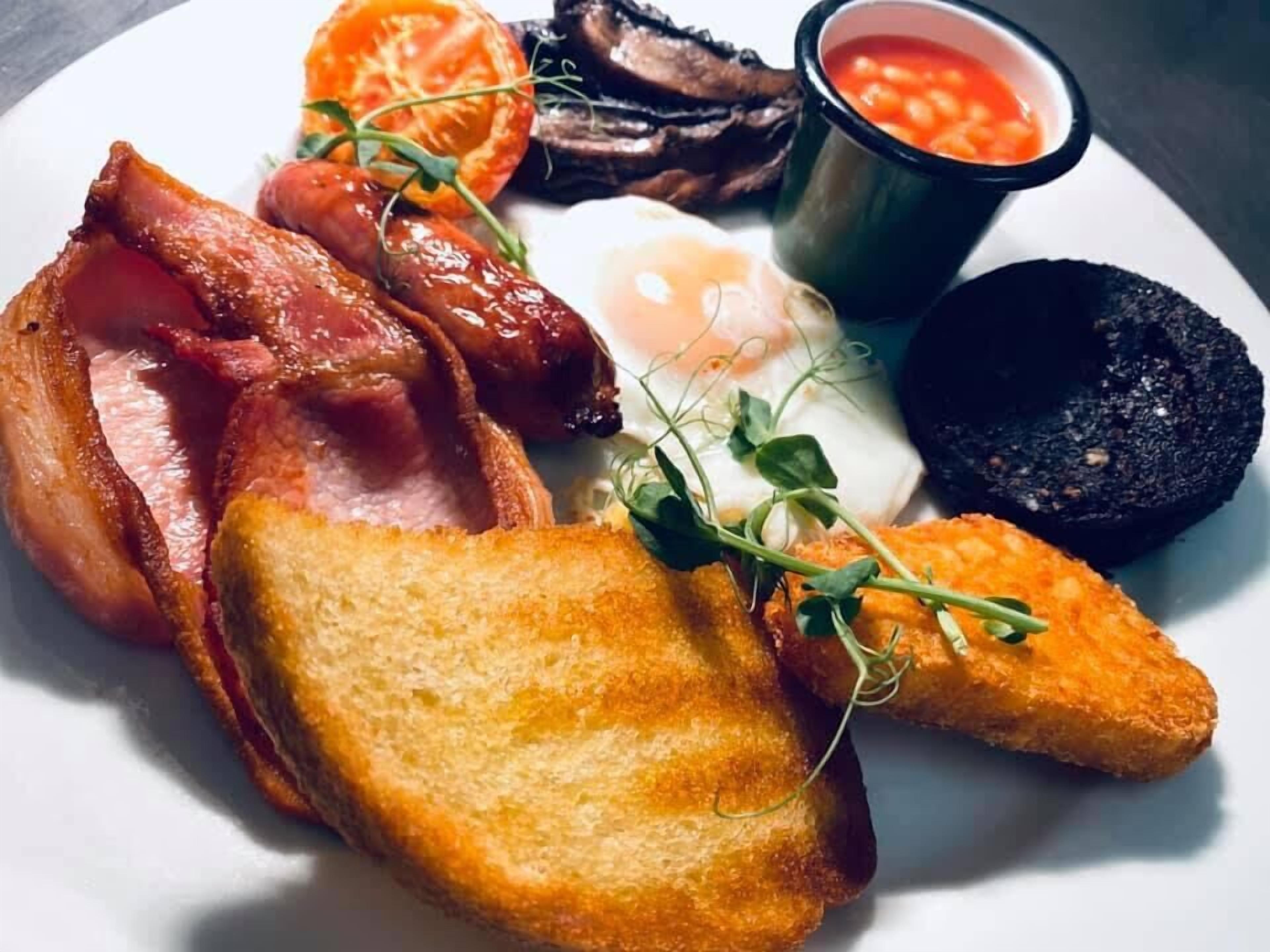 A plate of breakfast food including bacon, eggs, toast, and beans.
