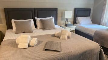 A hotel room with two beds, each with a headboard, a bedside table with a lamp, and a small box of tissues.