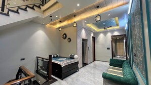 Een ruime woonkamer met een hoge plafond, een trap, een bank en een bed.