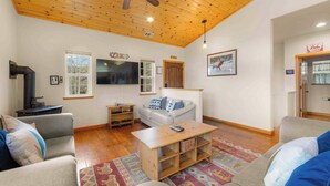 Un salon chaleureux avec un plafond en bois, un téléviseur à écran plat, un canapé, une table basse et une cheminée.