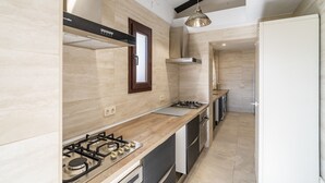 A modern kitchen with a gas stove, wooden countertop, and stainless steel appliances.
