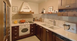 A kitchen with wooden cabinets, a stove, a sink, and a dishwasher. - Sea Horizon Spacious Sea View Villa for Families and Groups (Halkidiki)