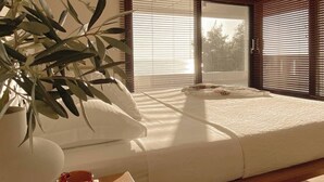 A bedroom with a bed, a plant, and a table with a glass. - Sea Horizon Spacious Sea View Villa for Families and Groups (Halkidiki)