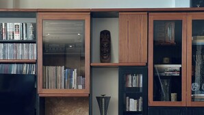 A living room with a wooden cabinet, a television, and a remote control on a table. - Sea Horizon Spacious Sea View Villa for Families and Groups (Halkidiki)
