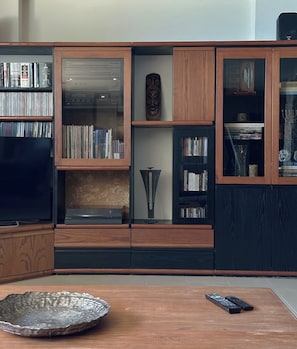 A living room with a wooden cabinet, a television, and a remote control on a table. - Sea Horizon Spacious Sea View Villa for Families and Groups (Halkidiki)