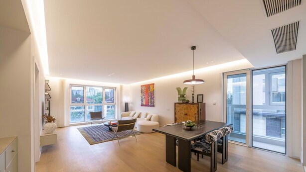 A spacious living area with a dining table, sofa, and large windows offering city views. - Book and Bed-Chang Ning (Shanghai)