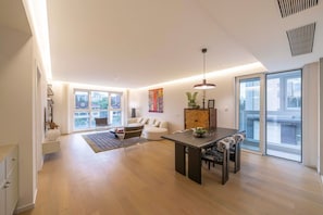 A spacious living area with a dining table, sofa, and large windows offering city views. - Book and Bed-Chang Ning (Shanghai)