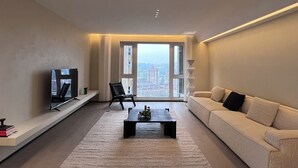 A modern living room with a large window, a sofa, a coffee table, and a TV. - Book and Bed-Chang Ning (Shanghai)