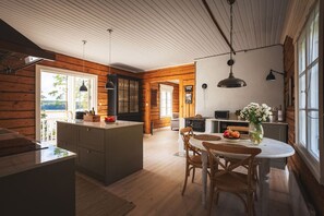 A spacious kitchen with wooden walls, a dining area with a round table, and a view of the outdoors.