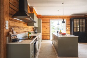 A modern kitchen with wooden walls, a central island, and a view to the outside.