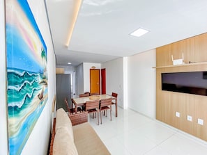 Una sala de estar moderna con comedor, un cuadro grande y un televisor en la pared.