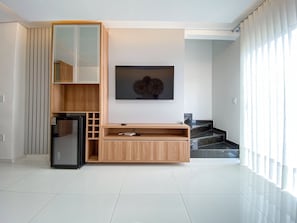 Uma sala de estar moderna com um sistema de entretenimento embutido, uma TV de tela plana e uma escada que dá acesso a outro andar.