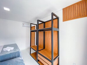 Una habitación con literas, un armario y una mesita.