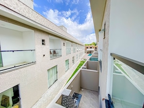 A multi-story building with balconies, a swimming pool, and a garden area. - Residencial Jardins de Taperapuã 2 (Porto Seguro)