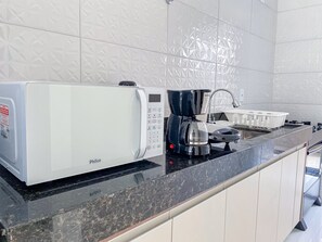 A kitchen with a microwave, coffee maker, and a sink. - Residencial Jardins de Taperapuã 2 (Porto Seguro)