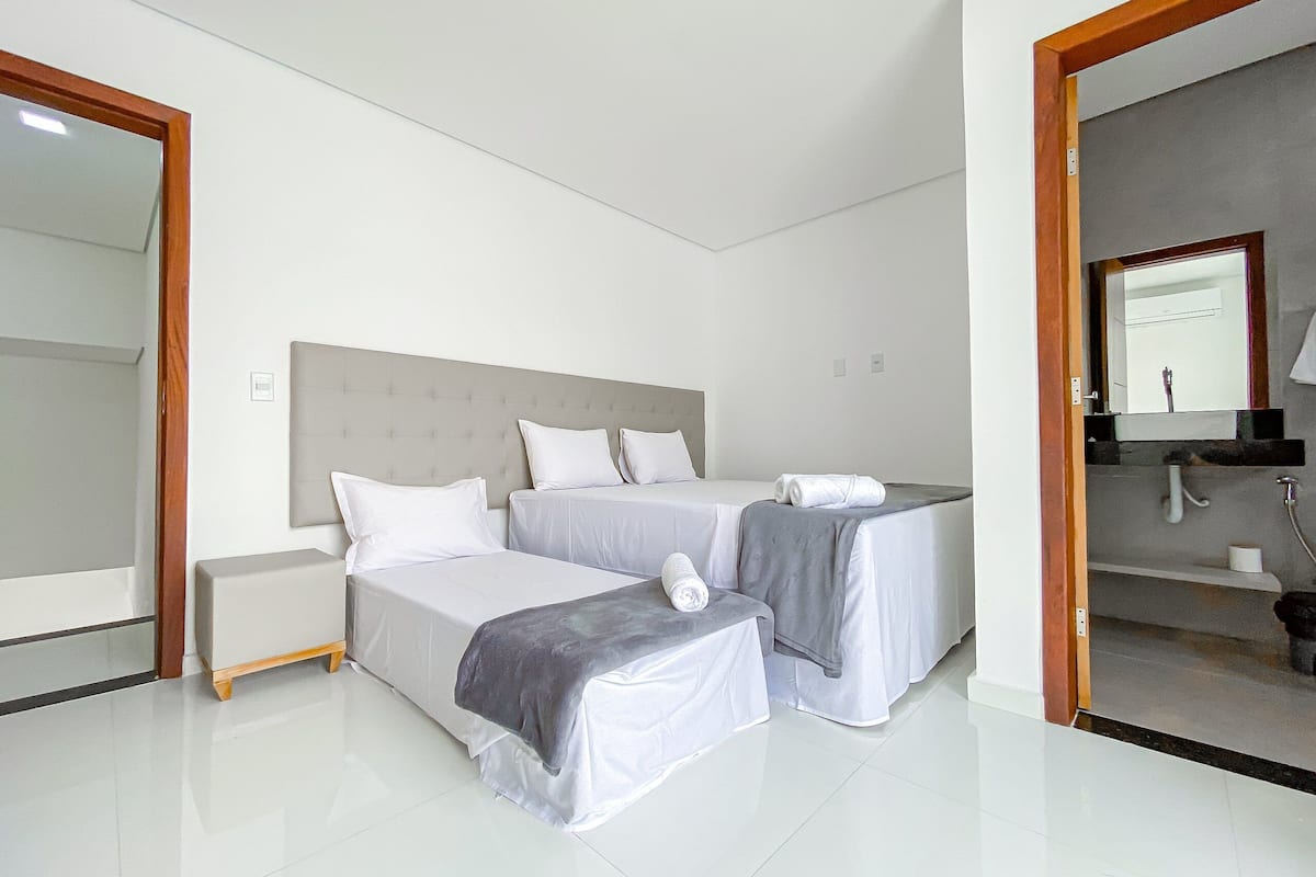 A hotel room with two beds, a large mirror, a bathroom with a sink and mirror, and a tiled floor.